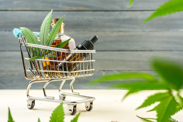 Supermarket trolley with marijuana leafs and medical cannabis oil cbd