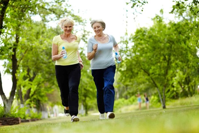 Portrait of two senior females running outdoors