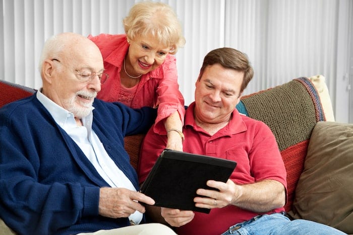 Adult son and elderly parents using their tablet PC at home.