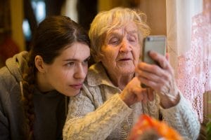 Elderly woman looks at a smartphone, with his adult granddaughter, at home.