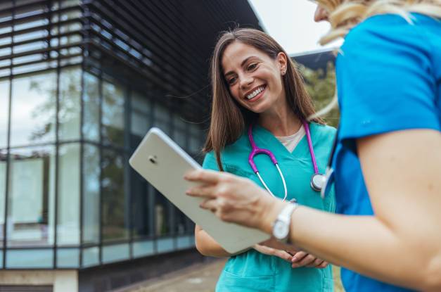 Two female doctors stand outside of an assisted living facility with a clipboard, ensuring every resident evacuates safely.