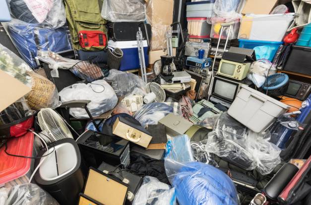 A pile of items inside of a room completely covering the floor. There's a fan, a television, and various boxes.